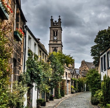 Historic cobblestone street in Edinburgh's Circus Lane with stone houses and St Stephen's Church tower.