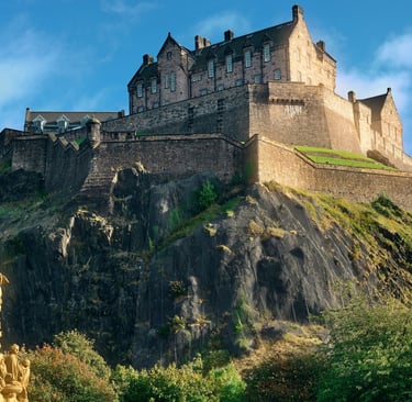 Panoramic view of the historic Edinburgh Castle atop Castle Rock in Scotland under a blue sky.