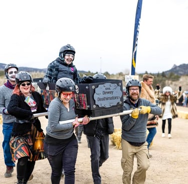 A costumed team carries a decorated coffin in a coffin race at a mountain winter festival.