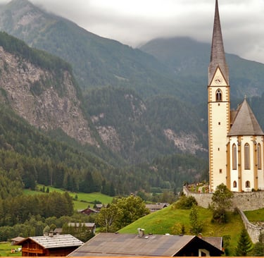 A scenic view of St. Vincent Church in the Austrian Alps village of Heiligenblut during a cloudy day.