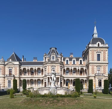 Exterior view of the historic Hermesvilla palace architecture in Vienna with statue and gardens.