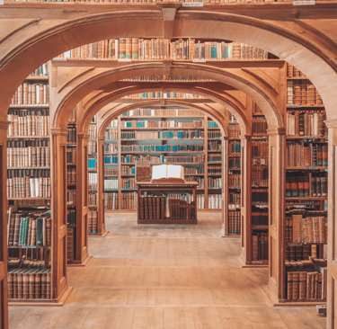 Ancient library interior with symmetrical wooden arches and shelves filled with vintage leather-bound books.