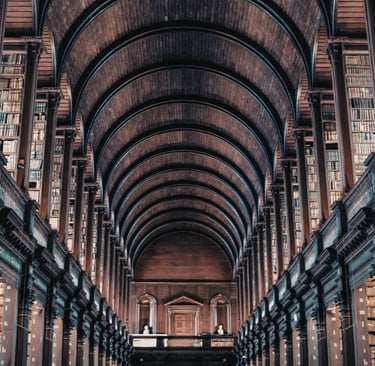 The historic Long Room at Trinity College Dublin library featuring high vaulted ceilings and wooden bookshelves.