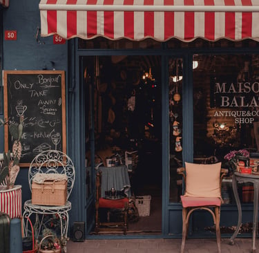 Exterior of Maison Balat antique and coffee shop in Istanbul with a red striped awning and vintage decor.
