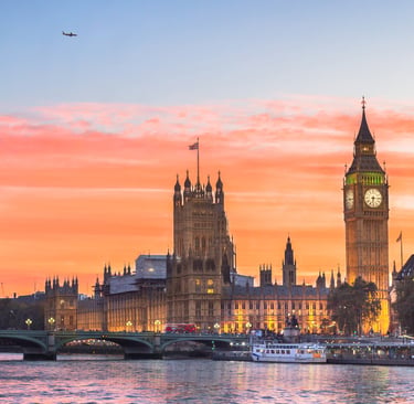 A panoramic view of Big Ben and the Houses of Parliament in London during a vibrant sunset over the River Thames.