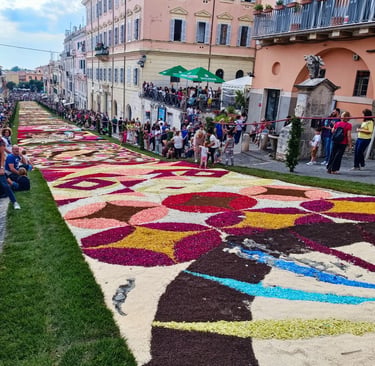 A colorful floral carpet mosaic lines a historic street during the Infiorata festival in Genzano, Italy.