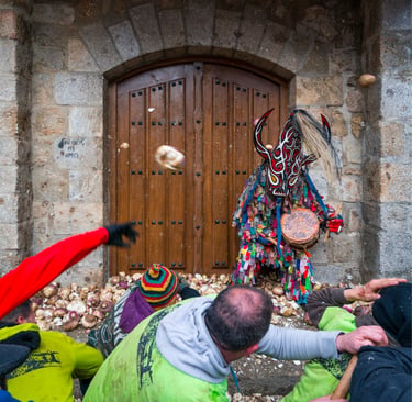 People throwing turnips at Jarramplas wearing a colorful masked costume during a Spanish festival.