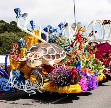 Colorful aquarium-themed parade float featuring a large sea turtle and vibrant coral decorations.