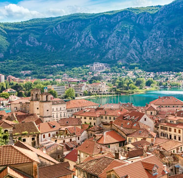 Panoramic view of the red tile roofs in the historic Old Town of Kotor, Montenegro, nestled against lush green mountains and