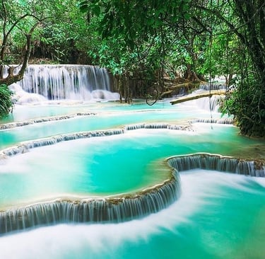 Kuang Si Falls features multi-tiered turquoise limestone pools and cascading waterfalls in a lush tropical jungle.