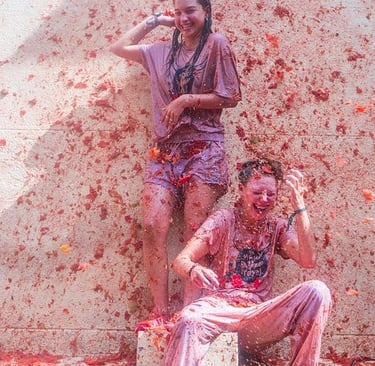 Two people laughing and covered in pulp during the La Tomatina tomato food fight festival in Spain.