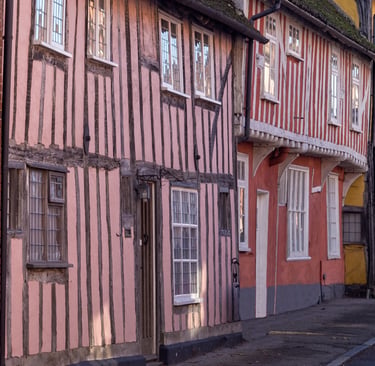 Historic timber-framed medieval houses in Lavenham, Suffolk, featuring colorful plaster facades.