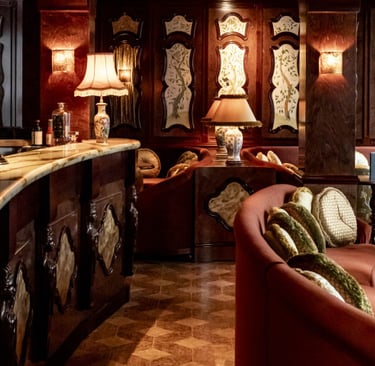 Elegant vintage hotel bar with marble counter, plush seating, and warm ambient lighting.