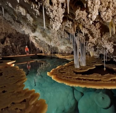 A lone adventurer explores an ancient cave with stunning stalactites, stalagmites, and crystal-clear turquoise water