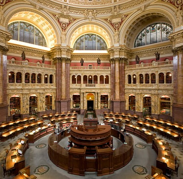 Interior view of the ornate Main Reading Room at the Library of Congress in Washington DC with domed architecture.