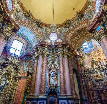 Ornate gold and marble interior of a Spanish Baroque church with intricate sculptures.
