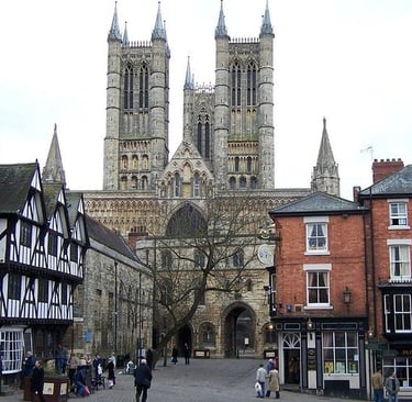 The historic Lincoln Cathedral towers over traditional Tudor architecture in Lincoln's medieval Castle Hill square.