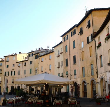 Historic Piazza dell'Anfiteatro in Lucca with yellow buildings and outdoor cafe seating.