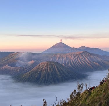 Sunrise view of Mount Bromo and Mount Semeru volcanoes rising above morning mist in Indonesia.