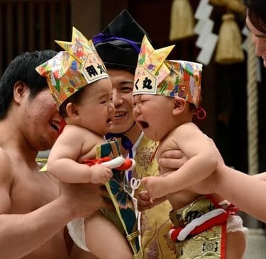 Two crying babies wearing paper crowns compete in a traditional Japanese Nakizumo baby crying contest.