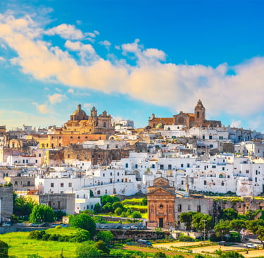 Panoramic view of Ostuni, the White City in Puglia, Italy, featuring historic whitewashed buildings and a blue sky.