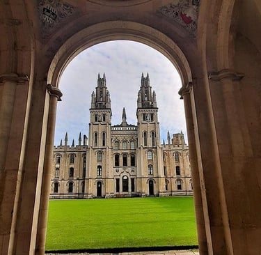 A view of the Gothic twin towers at All Souls College, Oxford University, framed by a stone archway.