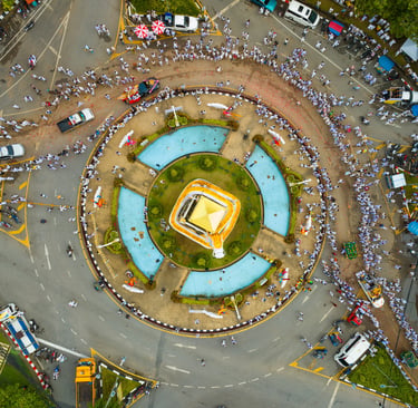 Aerial view of a Phuket Vegetarian Festival parade circling a city roundabout with crowds in white.