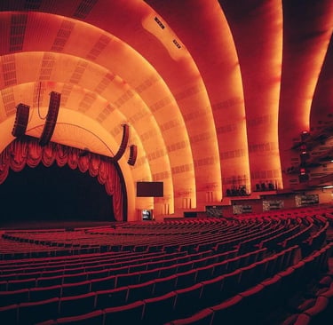 Interior of Radio City Music Hall stage and red seating with Art Deco arched ceiling.