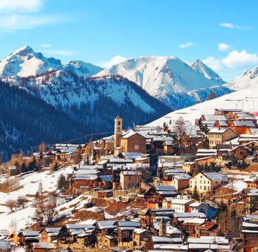 Panoramic view of a snow-covered alpine village nestled in the French Alps with scenic mountain peaks.
