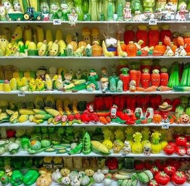 Collection of colorful vintage vegetable salt and pepper shakers organized on shelves.