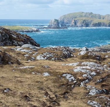 Rugged coastal landscape of the Scottish Highlands overlooking the blue Atlantic Ocean and rocky islands.