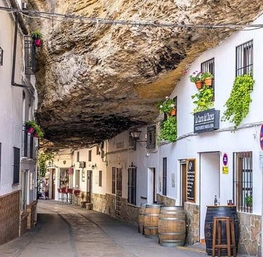 White houses built into a massive rock overhang in Setenil de las Bodegas, Spain.