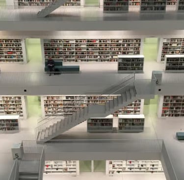 Modern white minimalist library interior with multiple floors, stairs, and book-filled shelves.