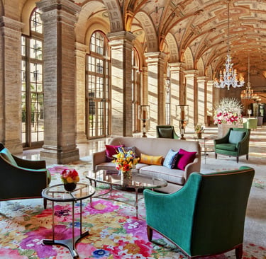 Elegant hotel lobby with vaulted ceilings, crystal chandeliers, and colorful floral carpets.