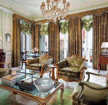 Elegant Venetian luxury suite featuring antique furniture, ornate gold mirrors, and green damask curtains.