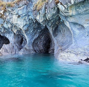 The Marble Caves in Patagonia featuring swirling blue rock patterns over turquoise glacial water.
