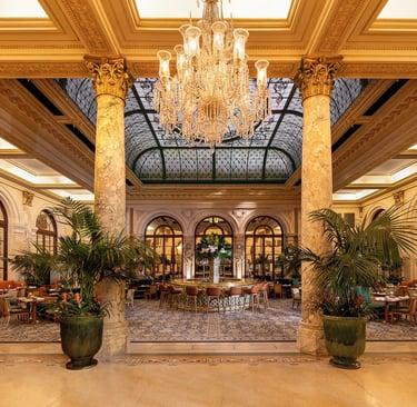 Elegant luxury hotel dining room with crystal chandelier, marble columns, and a stained glass ceiling.