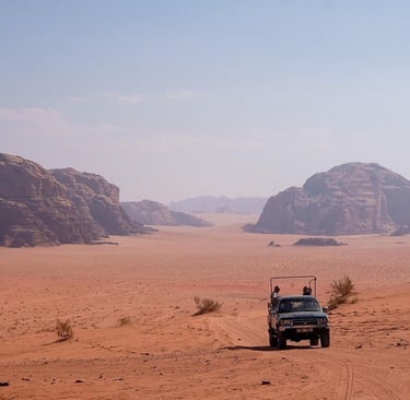 A 4x4 jeep safari tour driving through the red sand dunes and rock formations of Wadi Rum desert in Jordan.