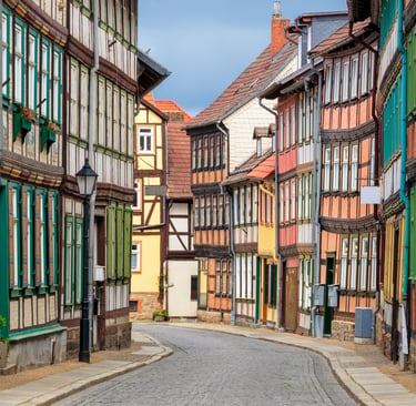 Traditional colorful half-timbered houses lining a cobblestone street in a historic German village.