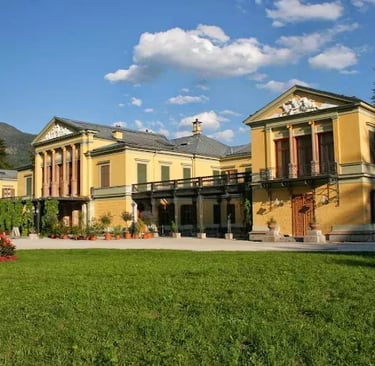 Yellow neoclassical imperial villa architecture with a green lawn and blue sky in Bad Ischl, Austria.