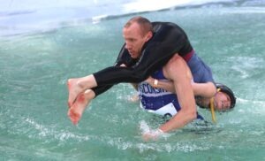 A man carries his teammate through a deep water obstacle during a competitive wife carrying race.