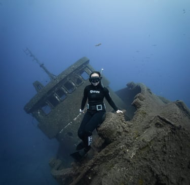 a freediver posing over a wreck ship. Photo taken by Sébastien Saintignan