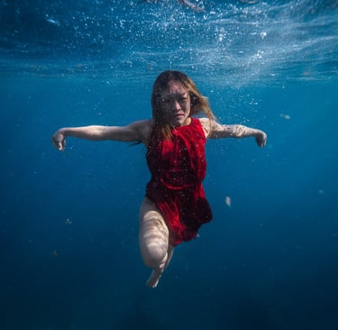 Model in red dress dancing underwater. Photo taken by Sébastien Saintignan 