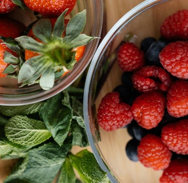 Strawberries with raspberries and blueberries in separate glass bowls