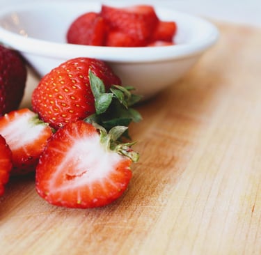 Whole and sliced strawberries in white bowl on table