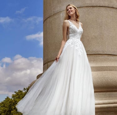 a woman in a white dress standing on a stone pillar