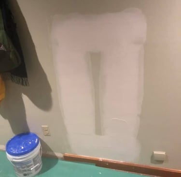 a bucket of joint compount on the floor of a room in front of a drywall repair