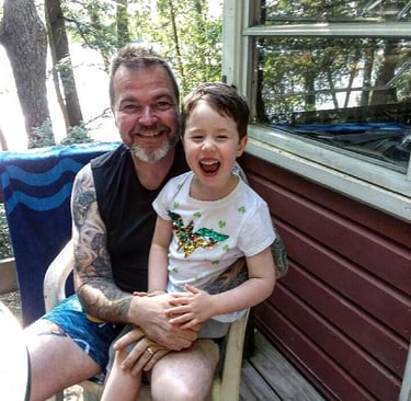 Sitting by a lake in Maine with my niece in August of 2019.