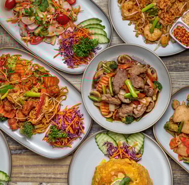 Overhead view of a large assortment of authentic Thai dishes, including beef and vegetable stir-fry