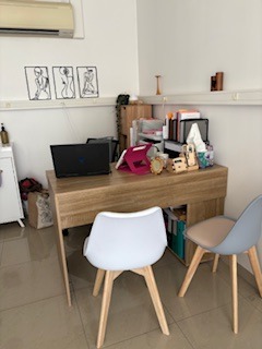 A tidy home office setup featuring a wooden desk, laptop, and two modern chairs.